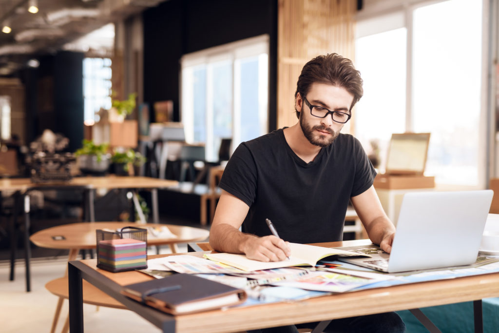 Freelancer,Bearded,Man,In,T-shirt,Taking,Notes,At,Laptop,Sitting