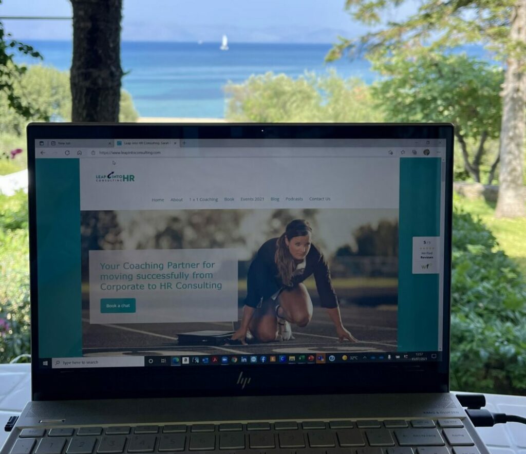 a laptop is open for work with the sea in Corfu as backdrop