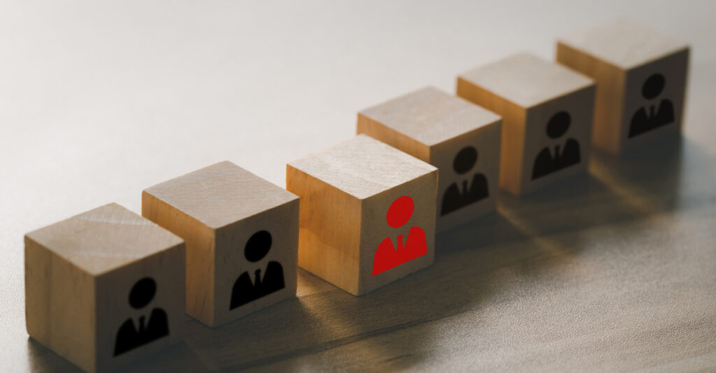 Leadership and teamwork concept.The red businessman icon on a wooden cube in front of other black businessman icons wooden cubes. Leadership and different thinking concepts. "n"n